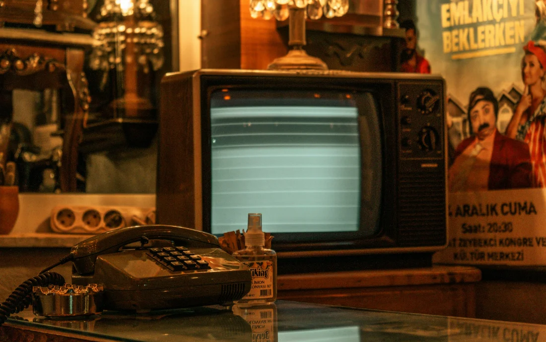 A television and a desk telephone in a warmly lit shop, the screen carrying nothing but static.