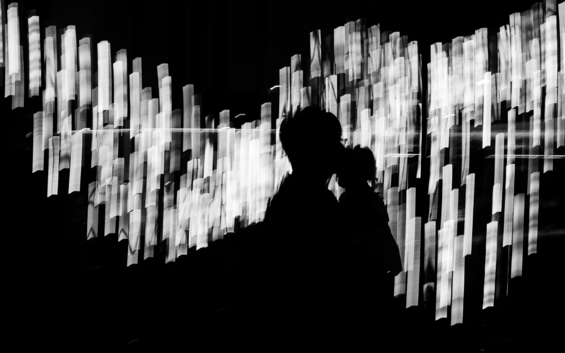 A silhouetted figure in front of a wall of tall, blurred panels of light.