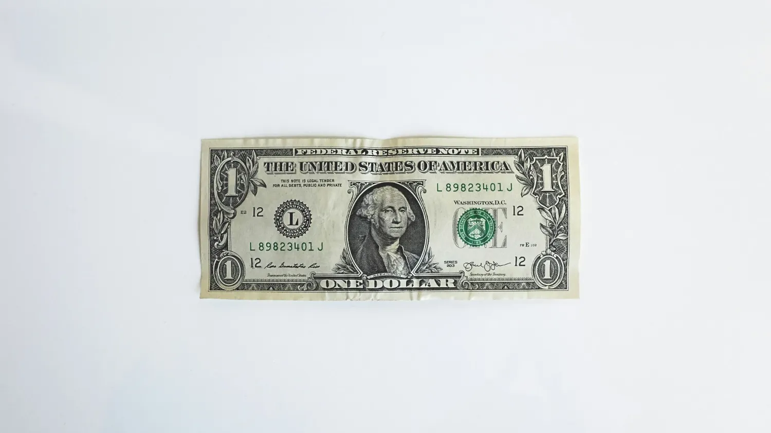A single dollar note lying flat on a white surface.