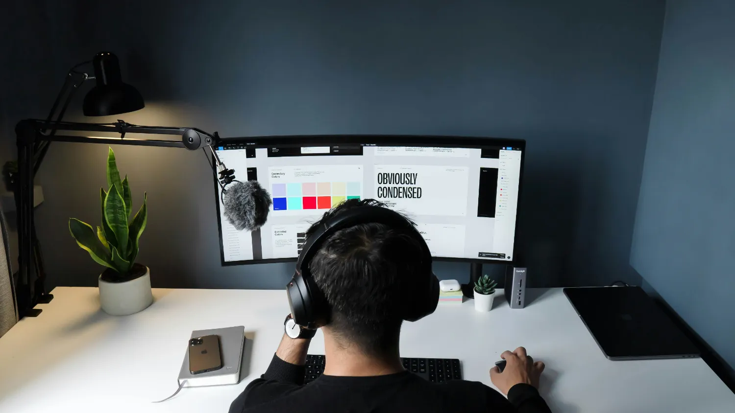 Someone working at a desk on a page layout, wearing headphones.