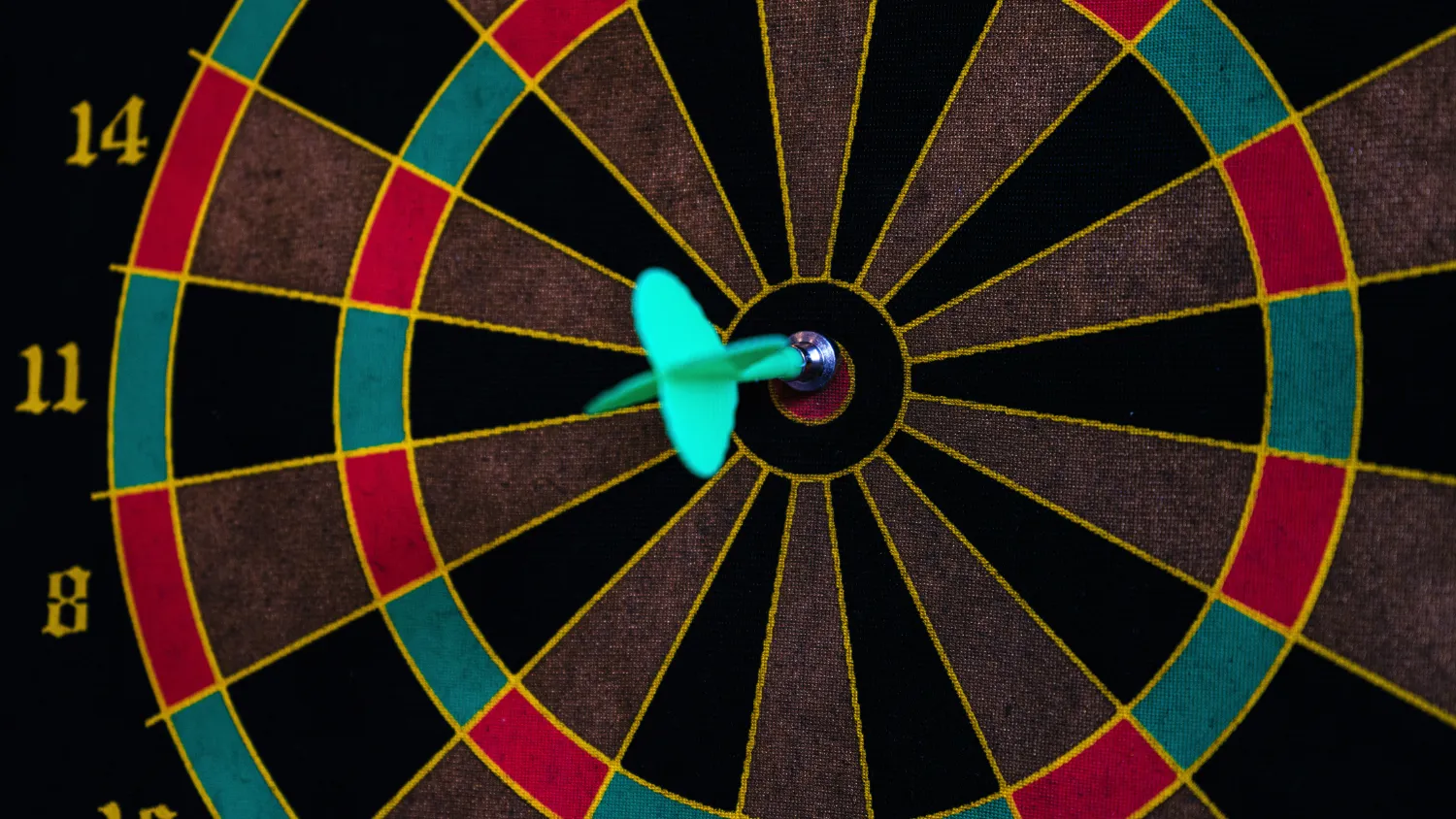 A dart sitting in the bullseye of a dartboard.