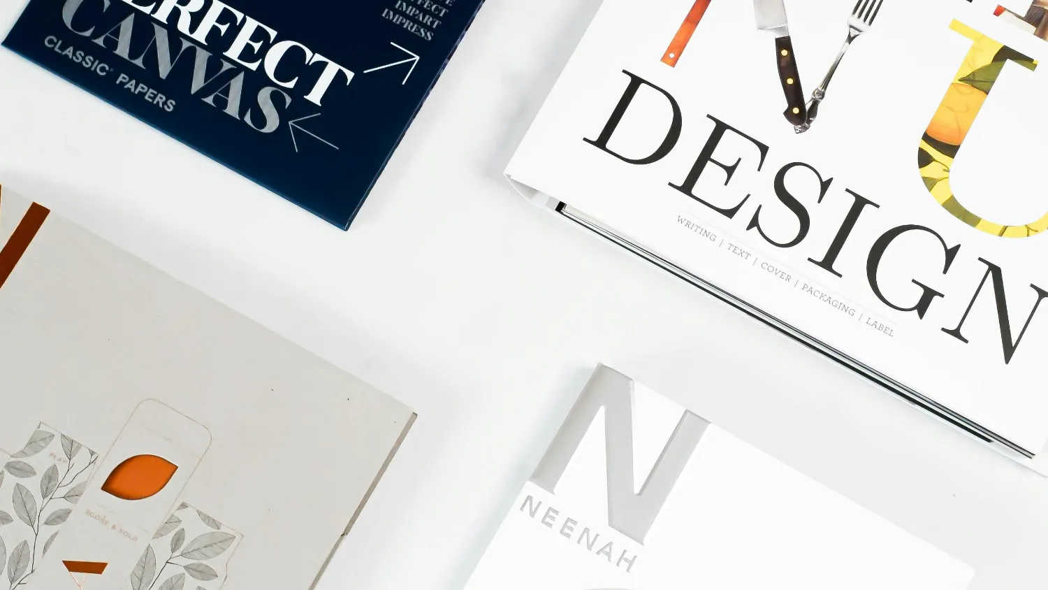 Printed brochures and layouts spread across a studio table.