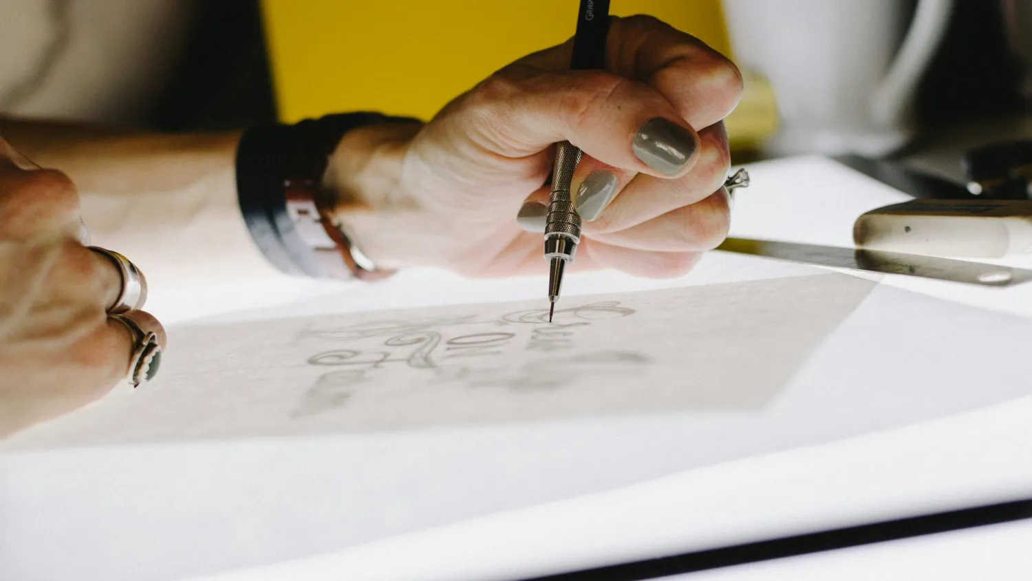 Logo sketches worked up in pencil across a sheet of layout paper.