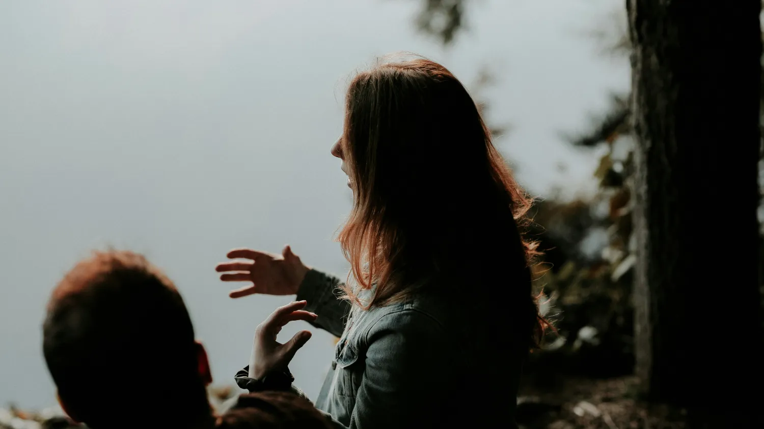 Two people talking outdoors, one of them mid-sentence with her hands raised.